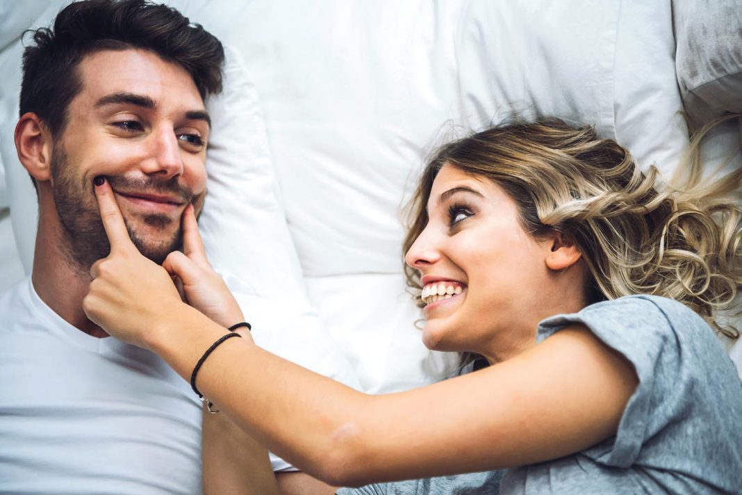 Cheerful couple playing in bed